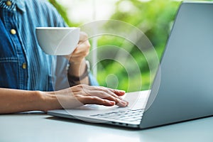A woman working and touching on laptop computer touchpad while drinking coffee in office
