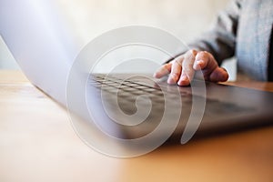 A woman working and touching on laptop computer touchpad on wooden table