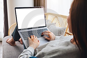 A woman working and typing on laptop computer with blank screen while lying on a sofa at home