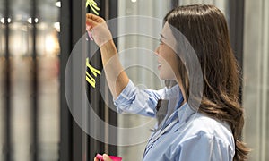 A woman working and use post it notes to share idea on the glass window in office. Business people work on project planning board