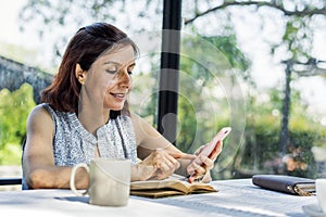 Woman working using mobile phone on an outdoor cafe