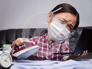 Woman working with very busy business and housework part, ironing cloth, talking on phone and working with laptop during isolation