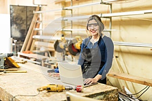 Woman working in a woodshop with laptop photo