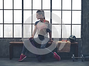 Woman in workout gear posing in profile on loft gym bench