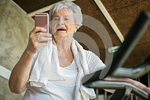 Woman workout in gym. Woman using smart phone on the elli