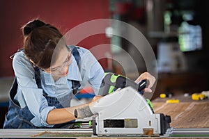 Woman works in a carpentry shop. Attractive female carpenter using some power tools for her work in a woodshop photo