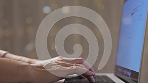 A woman works during the Christmas holidays. A girl is typing on a laptop in front of a photo of twinkling holiday