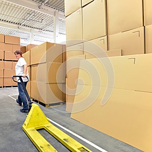 Woman works with forklift truck in a warehouse with cartons