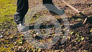 A woman works in the garden clean grass from the ground with a mop of hoe