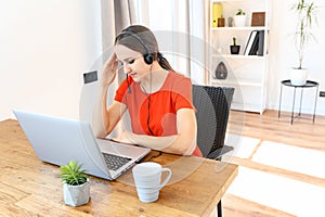 Woman works from home using headset and laptop