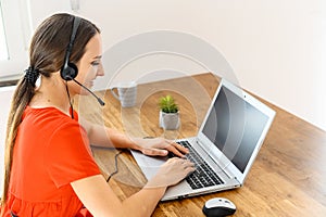 Woman works from home using headset and laptop