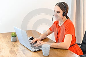 Woman works from home using headset and laptop