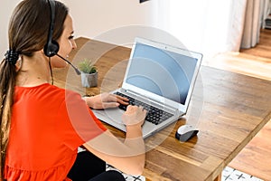 Woman works from home using headset and laptop