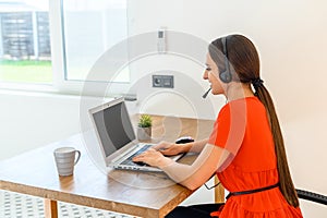 Woman works from home using headset and laptop