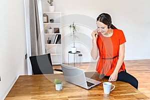 Woman works from home using headset and laptop