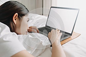 Woman works with laptop on the bed in concept of workation.