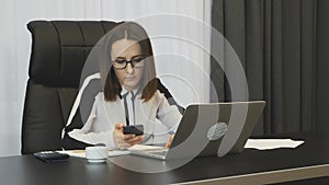 Woman works on laptop in office. Concentrated confident businesswoman working in modern office. Young female doing important job.