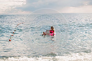 Woman works on laptop in sea. Freelancer, blond woman in sunglases floating on an inflatable big pink donut with a