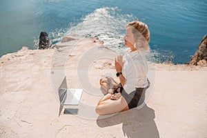 Woman works on laptop in sea. Freelancer, blond woman in sunglases floating on an inflatable big pink donut with a photo