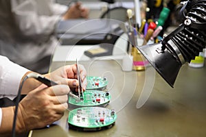 Woman works in manual assembly of electronic printed circuit b