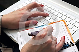 Woman works on a white laptop.