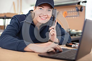 woman in workshop using laptop and talking on landline