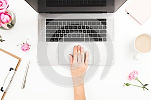 Woman workspace with female hands, laptop, pink roses bouquet, accessories, diary. Top view. Flat lay home office desk. Girl worki
