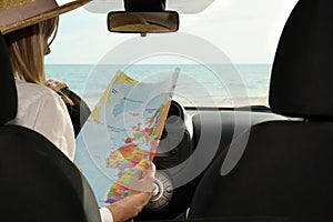 Woman with world map in car, back view. Road trip