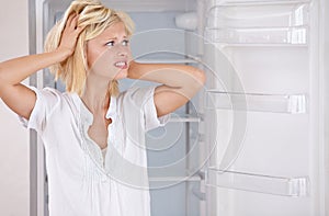 Woman, worried and empty fridge or stress for economic crisis in kitchen for starving problem in home. Female person