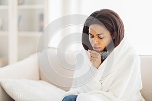 Woman Wrapped in Blanket Sitting on Couch, Coughing