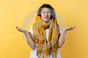 Woman wrapped in warm scarf, being helpless, crying suffering from flu symptoms, feels unwell.