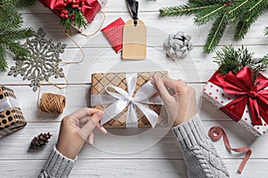 Woman wrapping Christmas gift at wooden table