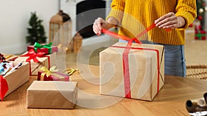 Woman wrapping Christmas gift at wooden table indoors, closeup