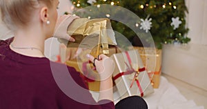 Woman wrapping Christmas present by fireplace at home