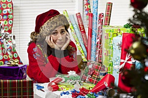 Woman wrapping Christmas presents, looking exhausted.