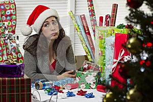 Woman wrapping Christmas presents, looking exhausted.