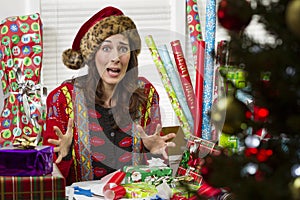Woman wrapping Christmas presents, looking frustrated.