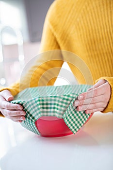 Close Up Of Woman Wrapping Food Bowl In Reusable Environmentally Friendly Beeswax Wrap photo