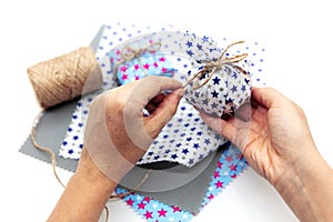 Woman is wrapping a gift with natural materials and organic cotton