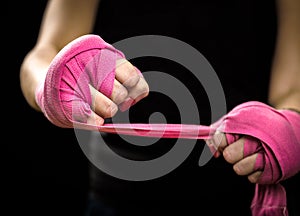 Woman is wrapping hands with pink boxing wraps