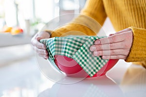 Close Up Of Woman Wrapping Food Bowl In Reusable Environmentally Friendly Beeswax Wrap photo