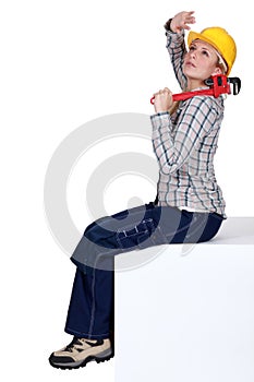 Woman with wrench shielding eyes