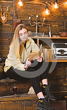 Woman writer in library at home creative occupation reading book. Girl in casual outfit sits with book in wooden vintage