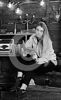 Woman writer in library at home creative occupation reading book. Girl in casual outfit sits with book in wooden vintage