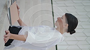 Woman writer typing outdoors. Girl writing text on laptop using notes vertical.