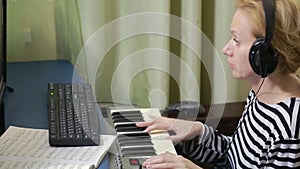 Woman writes music on the computer. digital piano midi keyboard