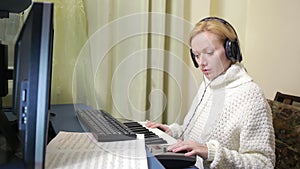 Woman writes music on the computer. digital piano midi keyboard