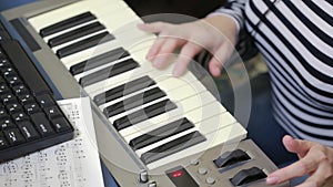 Woman writes music on the computer. digital piano midi keyboard