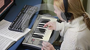 Woman writes music on the computer. digital piano midi keyboard