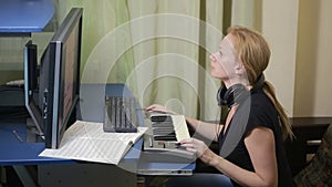 Woman writes music on the computer. digital piano midi keyboard